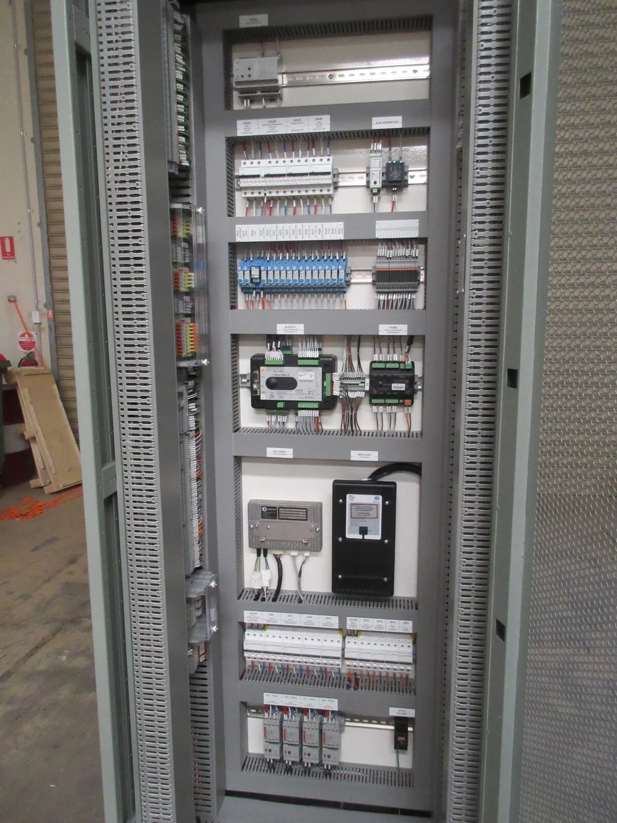 Interior of OEM control panel showing DIN rail wiring, terminal blocks, and PLC modules